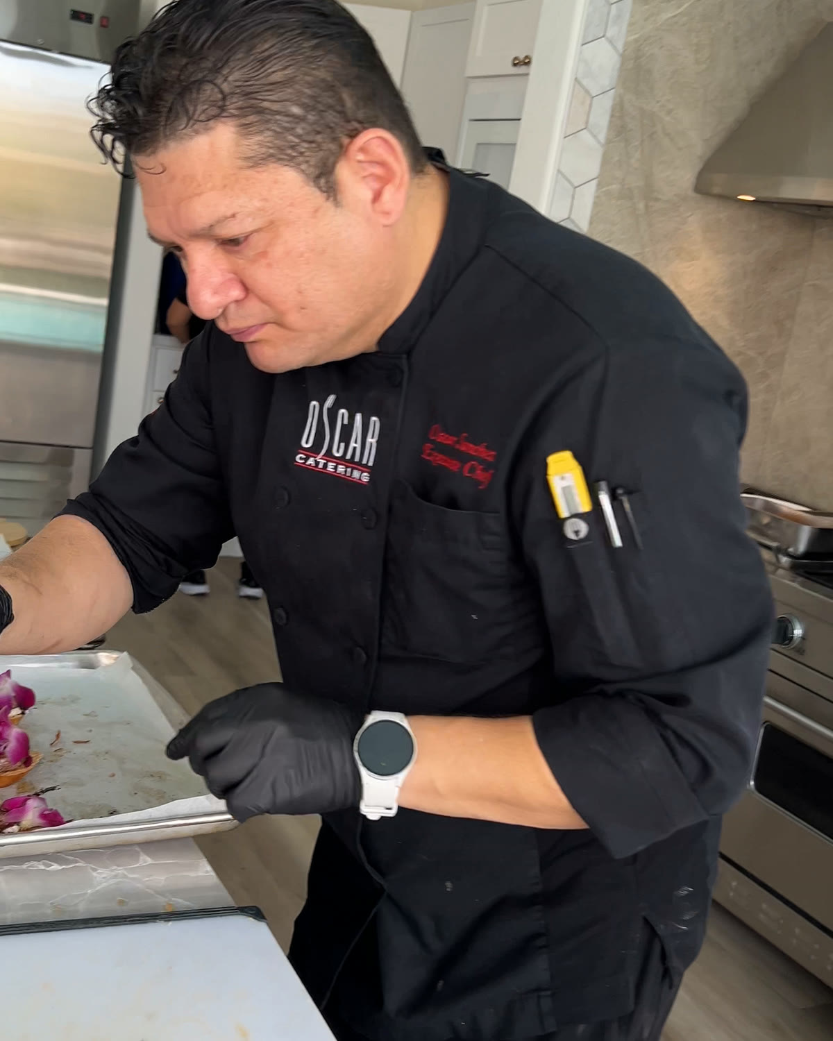 Chef Oscar Sanchez in his Oscar Catering chef jacket plating trays of appetizers in the villa kitchen