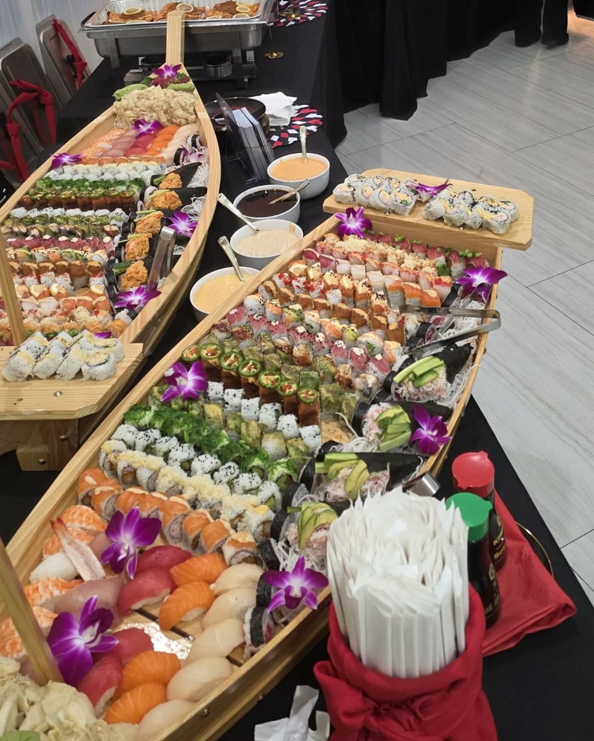 Two sushi boats leading a full buffet line at a private event