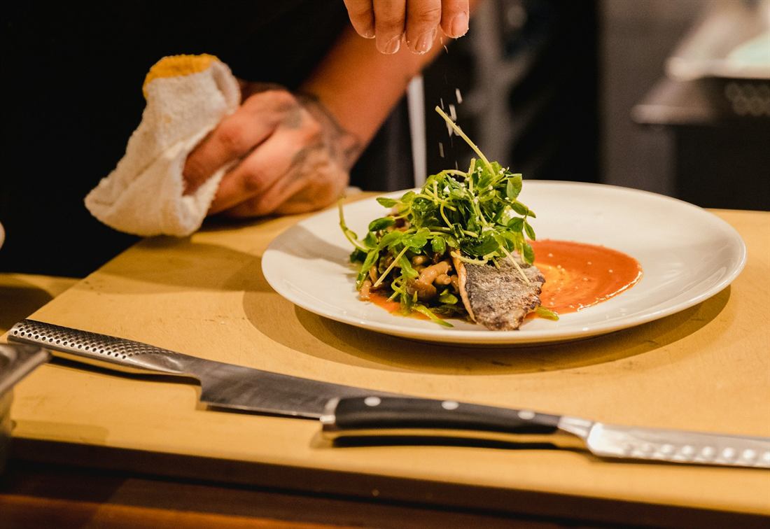 Chef finishing a plated dish with tweezers